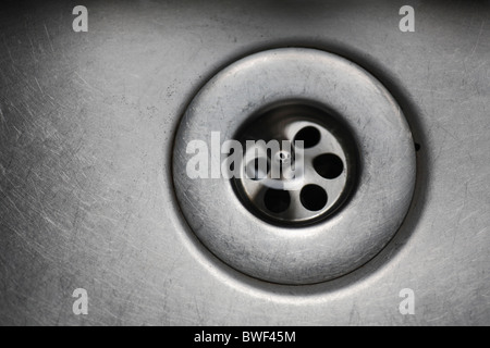 Acqua sparendo giù il foro del tappo in un lavandino. Foto Stock
