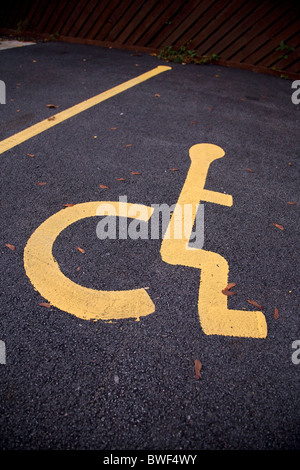 Sedia a rotelle disabili legati persona simbolo sulla pista di un bollino blu lo spazio per parcheggiare in un parcheggio Foto Stock