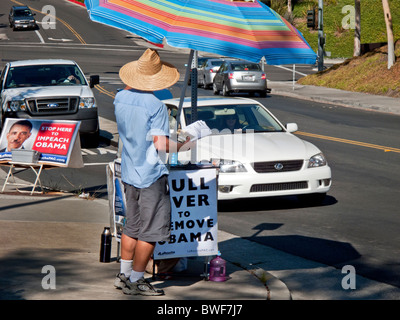 Un attivista che cercano di impeachment del Presidente degli Stati Uniti Barack Obama distribuisce da locandine di conducenti in transito in Laguna Niguel, CA. Foto Stock