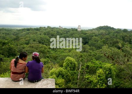 Due giovani donne godendo la vista dalla cima del tempio IV, Tikal, El Petén, Guatemala. Tikal è un sito Patrimonio Mondiale dell'UNESCO. Foto Stock