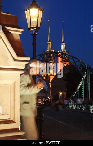 Busker suonare il flauto Tumski sul ponte, Cattedrale di San Giovanni Battista in background. Wroclaw, Bassa Slesia, Polonia. Foto Stock