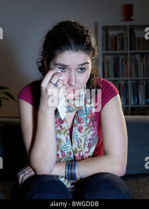 Giovane donna piange guardando la televisione Foto Stock