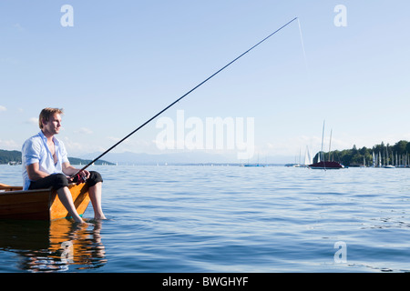 Imprenditore con canna da pesca in canotto Foto Stock