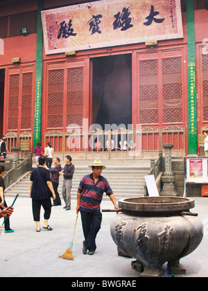 In alta montagna in Hangzhou, a un tempio, mentre un pulitore cinese sta con il suo pennello Foto Stock