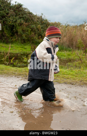 Un ragazzo giocando in una pozzanghera a Conwy RSPB riserva. Foto Stock