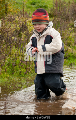 Un ragazzo giocando in una pozzanghera a Conwy RSPB riserva. Foto Stock