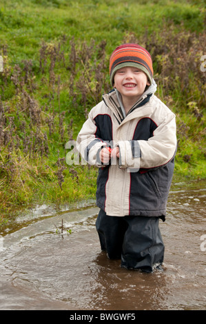 Un ragazzo giocando in una pozzanghera a Conwy RSPB riserva. Foto Stock