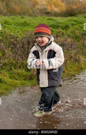 Un ragazzo giocando in una pozzanghera a Conwy RSPB riserva. Foto Stock