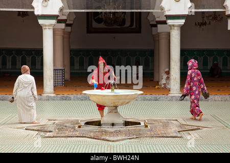 Femmina islamica adoratori di purificare se stessi in corrispondenza di una abluzione fontana a una moschea nella Medina, la città vecchia di Fes, Marocco. Foto Stock
