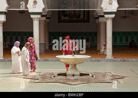 Islamico femmina adoratori di purificare se stessi in corrispondenza di una abluzione fontana a una moschea nella Medina, la città vecchia di Fes, Marocco. Foto Stock