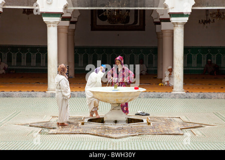Islamico femmina adoratori di purificare se stessi in corrispondenza di una abluzione fontana a una moschea nella Medina, la città vecchia di Fes, Marocco. Foto Stock