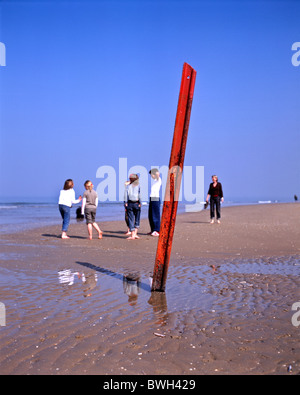 #2 di 3 : la gente sulla spiaggia dietro un verticali di colore rosso della linea ferroviaria che sporgono dalla sabbiosa spiaggia di Scheveningen, l'Aia, NL Foto Stock