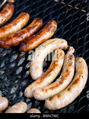 Cibo, carne, cottura, salsicce di essere cucinati su un barbecue barbecue grill esterno sui carboni ardenti. Foto Stock