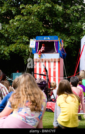 I bambini, intrattenimento, Punch e Judy Show, bambini seduti su erba guardando il tradizionale spettacolo di marionette. Foto Stock