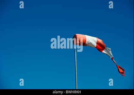 Strappati rosso e bianco nella manica a vento brezza leggera pianura contro il cielo blu. Foto Stock