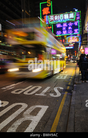 Autobus su occupato Hong Kong street di notte Foto Stock