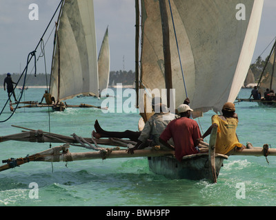 Oceano Indiano pesca dhow ngalawas tornando al Matemwe Zanzibar con equipaggio rilassato mentre altre barche hanno marinai sul bilanciamento del buttafuori Foto Stock