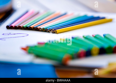 Matite colorate e pastelli a cera sul lato superiore della carta di libri d'arte messa a fuoco selettiva Foto Stock