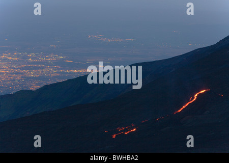 Il flusso di lava, luci di Catania nella valle, Parco dell'Etna National Park, lato nord del monte Etna, Sicilia, Italia Foto Stock