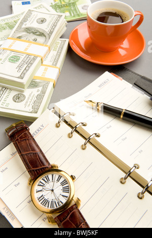 Immagine di aprire il blocco note con penna stilografica e guardare su di esso e rosso tazza di caffè con banconote di dollari nelle vicinanze Foto Stock