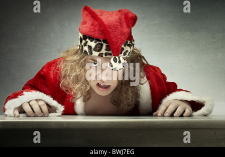 Angry Man in Santa Claus costume seduti al tavolo su un sfondo grungy Foto Stock