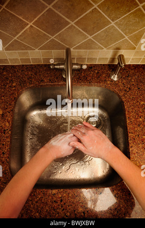 Panoramica di lavaggio a mano su un acciaio inox lavello da cucina Foto Stock