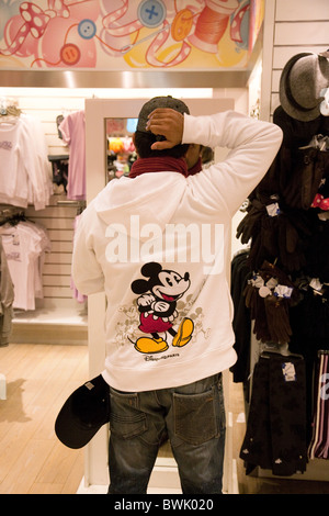 Un uomo che cerca su Disney vestiti in Disney Store, il villaggio di Disneyland Parigi, Francia Foto Stock