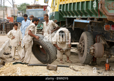 Gli uomini la modifica di un carrello pneumatico, Karachi, Pakistan Foto Stock