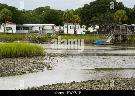 Un rimorchio costiere park & dock si siede accanto a una palude fangosa zone umide stream. Il grande airone bianco (airone) bird, sono numerosi qui. Foto Stock