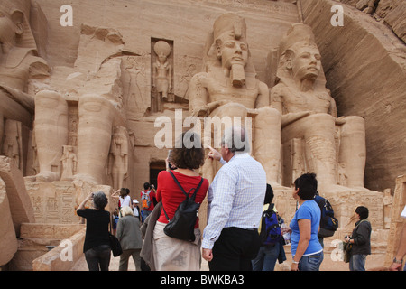 I turisti nella parte anteriore delle statue giganti al tempio di Ramses II, Abu Simbel Egitto, Africa Foto Stock