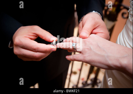 Lo sposo mettendo il matrimonio in sposa Foto Stock