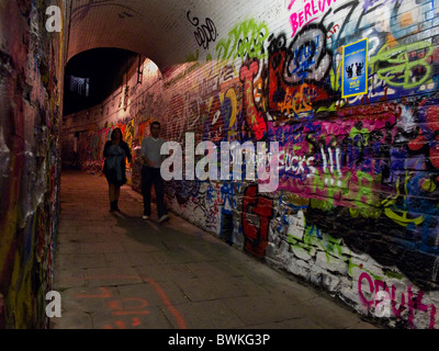 Due pedoni a piedi passato graffiti in 'graffiti vicolo' in Gent, Belgio poco prima della mezzanotte Foto Stock