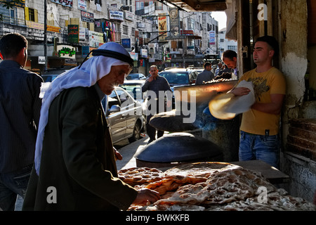 Un palestinese in abbigliamento tradizionale, scegliendo la pita in una strada di Ramallah Foto Stock