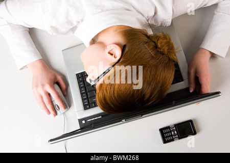 Immagine di molto stanco imprenditrice o studente mettendo la sua faccia sulla tastiera del notebook Foto Stock