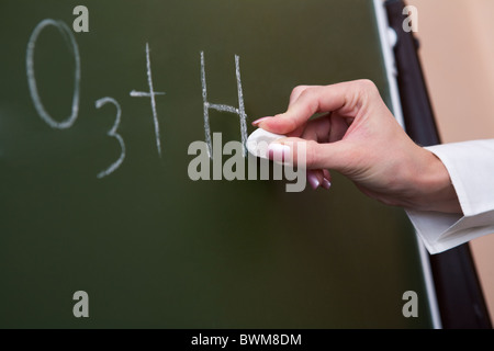 Close-up di femmine della mano che scrive sulla lavagna con chalk spiegando formula chimica Foto Stock