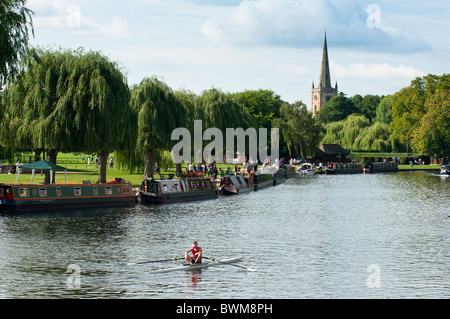 Una ripresa panoramica del fiume e lui chiesa della Santa Trinità come un vogatore va passato. Stratford upon Avon, Inghilterra. Foto Stock