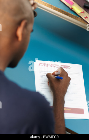 Guy riempiendo il modulo di domanda per i corsi di formazione post-laurea Foto Stock