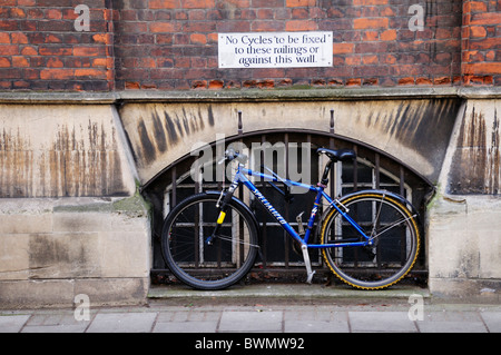 N cicli per essere fissati a questi steccati o contro questa parete segno, con incatenato al di sotto della bicicletta, Cambridge, Inghilterra, Regno Unito Foto Stock
