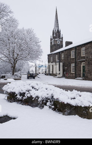 La Chiesa di Santa Maria di steeple, Burley in Wharfedale, siede dietro una fila di case coperte di neve. Foto Stock