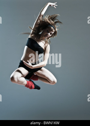 Bellissima giovane donna caucasica ragazza balletto ballerino breakdance salto salto su studio sfondo isolato Foto Stock