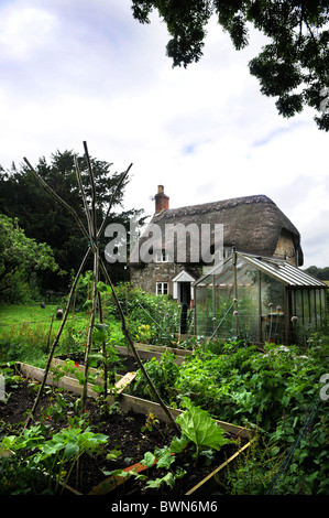 Un cottage con tetto di paglia con i polli in giardino Wiltshire, Regno Unito Foto Stock