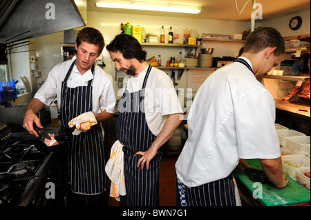 Capo Chef Stefano Terry (centro) è mostrata la colorazione di un pezzo di carne di maiale da Chef Ashley bosco presso il ristorante Hardwick Ab Foto Stock