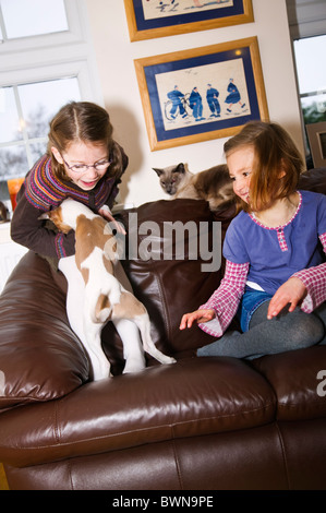 Due bambine a giocare con un cucciolo sul divano Foto Stock