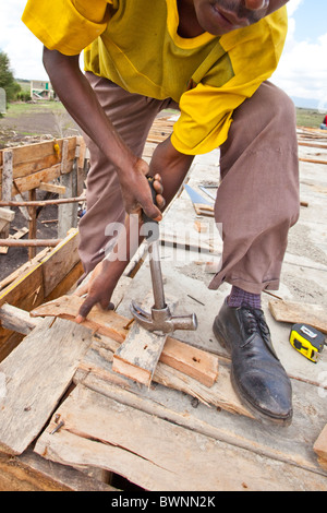 Workman aiutando costruire un edificio a Maji Mazuir Centro e scuola, Nairobi, Kenia Foto Stock