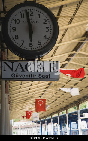 Turchia Istanbul Sultanahmet Stazione ferroviaria orologio sulla piattaforma con bandiere turche appeso dal tetto Foto Stock