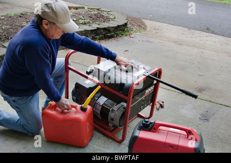 Un uomo si riempie il suo generatori con benzina come si prepara per i mesi invernali. Foto Stock