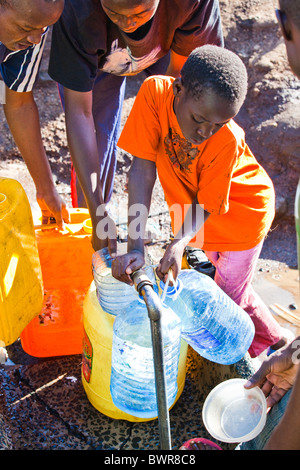 Il riempimento di bottiglie di acqua da un rubinetto installato di recente sul bordo di Mathare slum di Nairobi, in Kenya Foto Stock