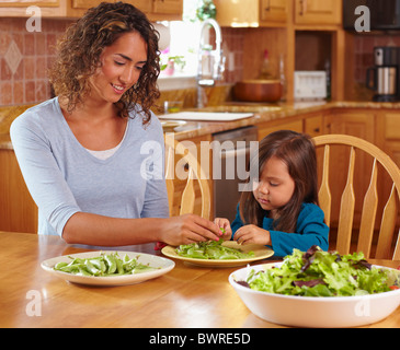 Madre e figlia piselli da sgranare al tavolo da pranzo Foto Stock