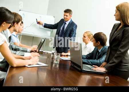 Immagine della Smart Business persone che guardano il loro leader mentre lui spiegare qualcosa su whiteboard durante il seminario Foto Stock