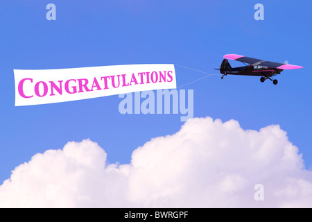 Un aereo di traino di un banner con la parola congratulazioni in rosa, buona per donne temi correlati o la nascita di una bambina Foto Stock